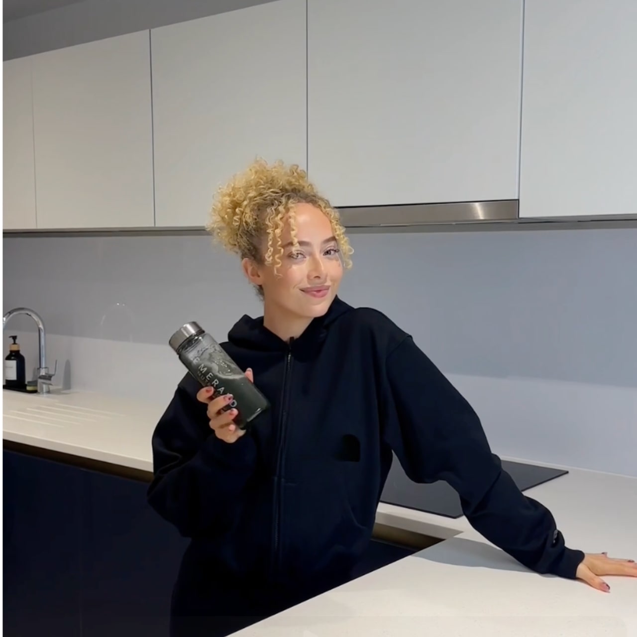 Person holding a water bottle in a kitchen setting