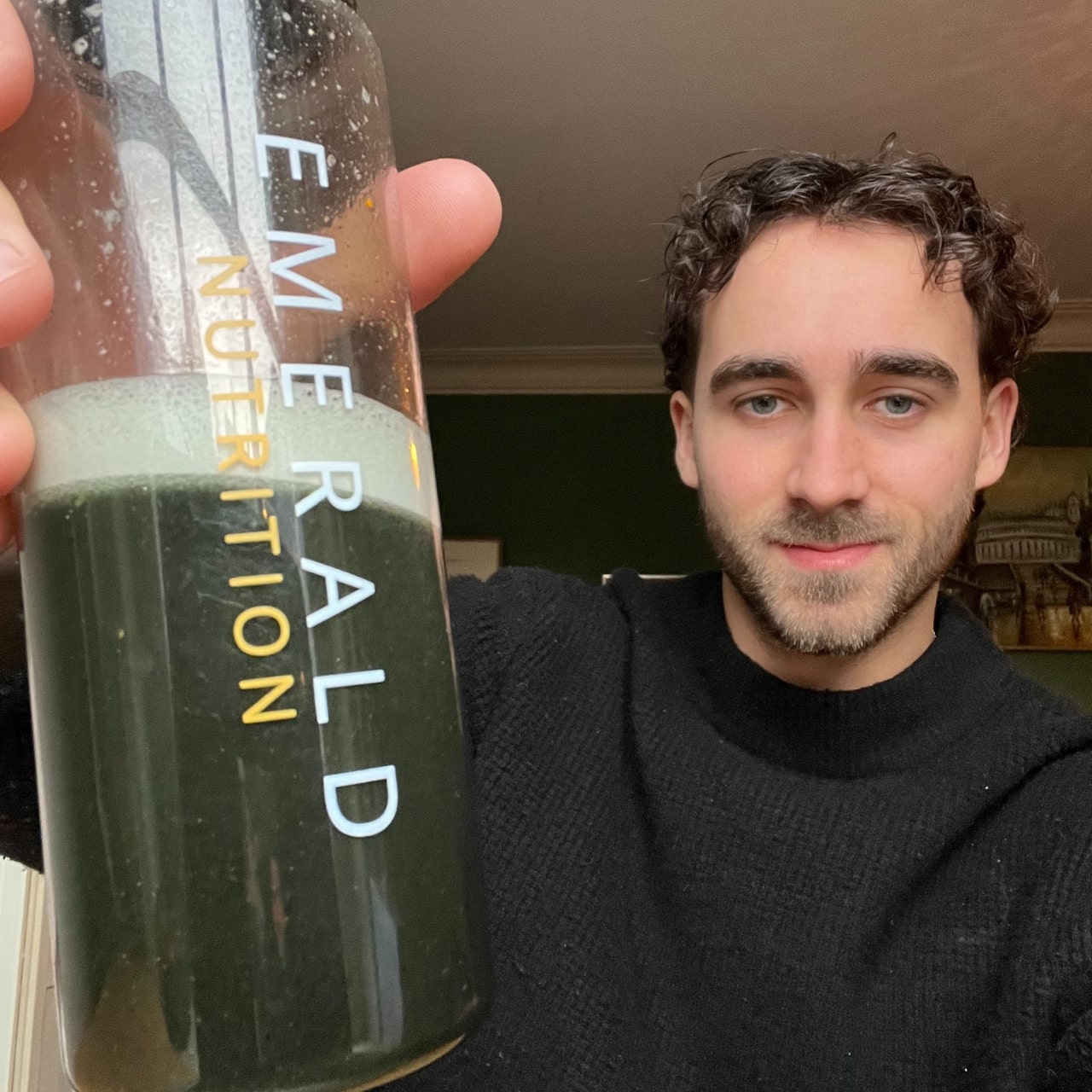 Person holding a bottle labeled 'Emerald Nutrition' in a kitchen setting