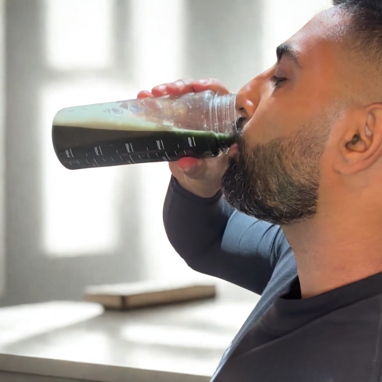 Man drinking from a bottle in a bright room