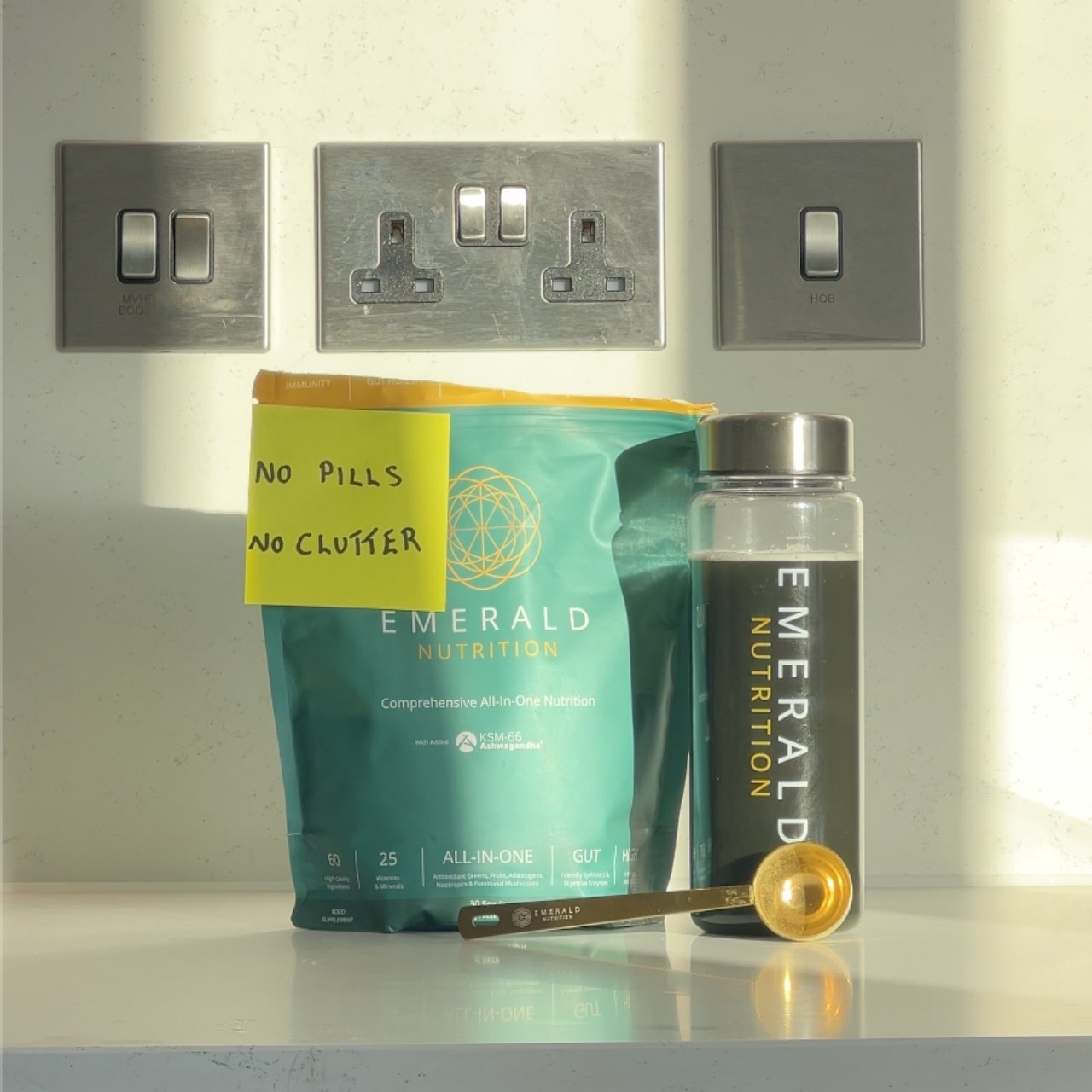 Emerald Nutrition supplement package with a jar and scoop on a kitchen counter.