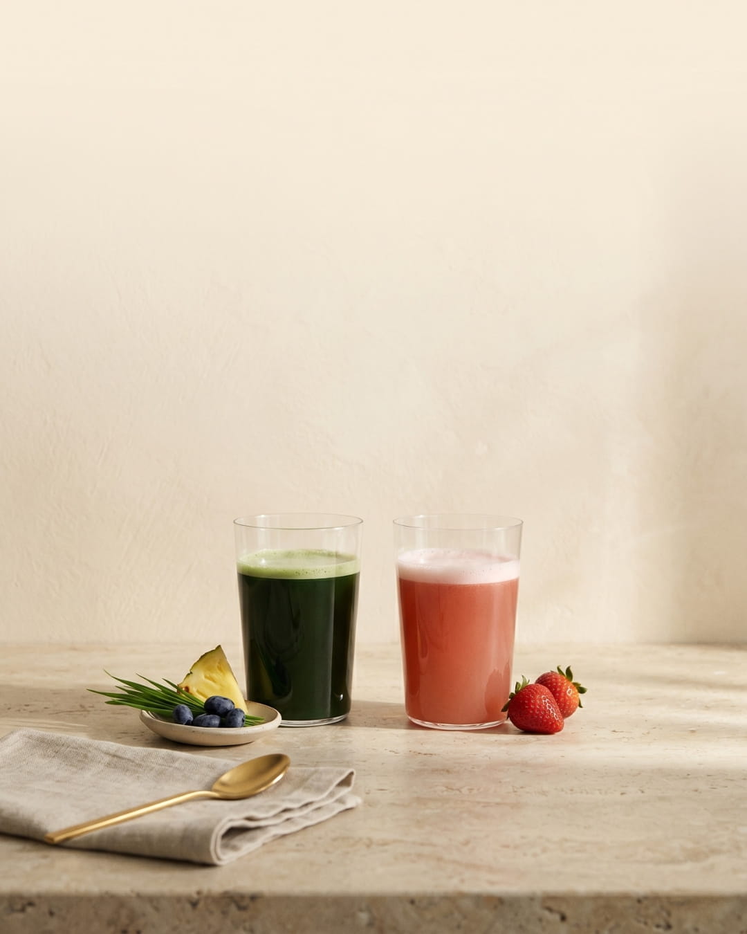 Emerald Nutrition Supergreens and Ignite drinks with fresh pineapple, haskap berries, strawberries and gold scoop on warm cream