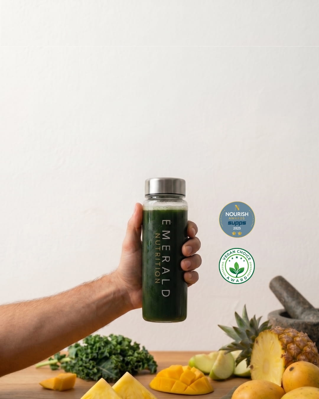 Emerald Nutrition Supergreens drink with fresh pineapple, haskap berries and gold scoop on warm cream