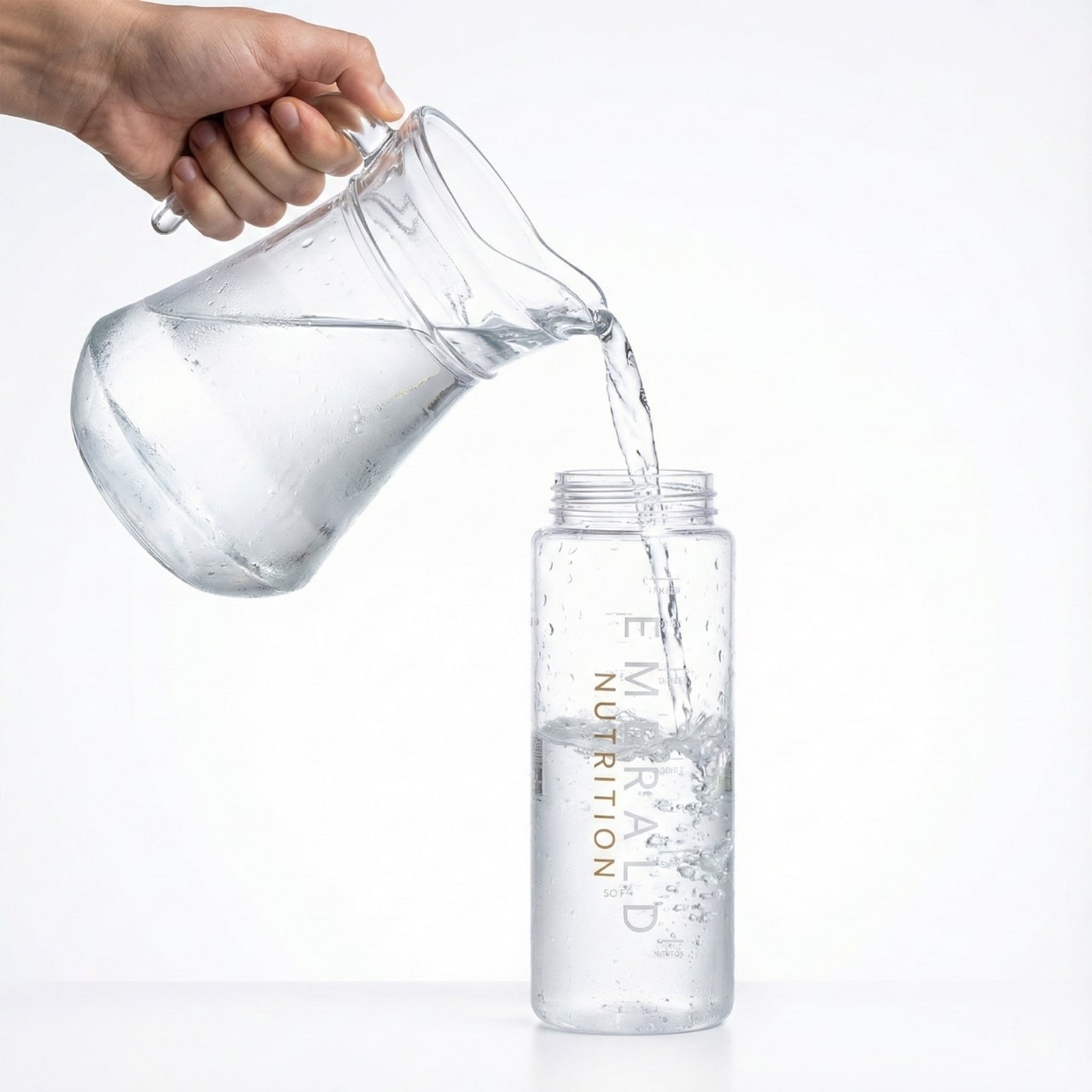 Clear pitcher pouring water into a clear bottle labeled 'Eminence Nutrition' on a white background