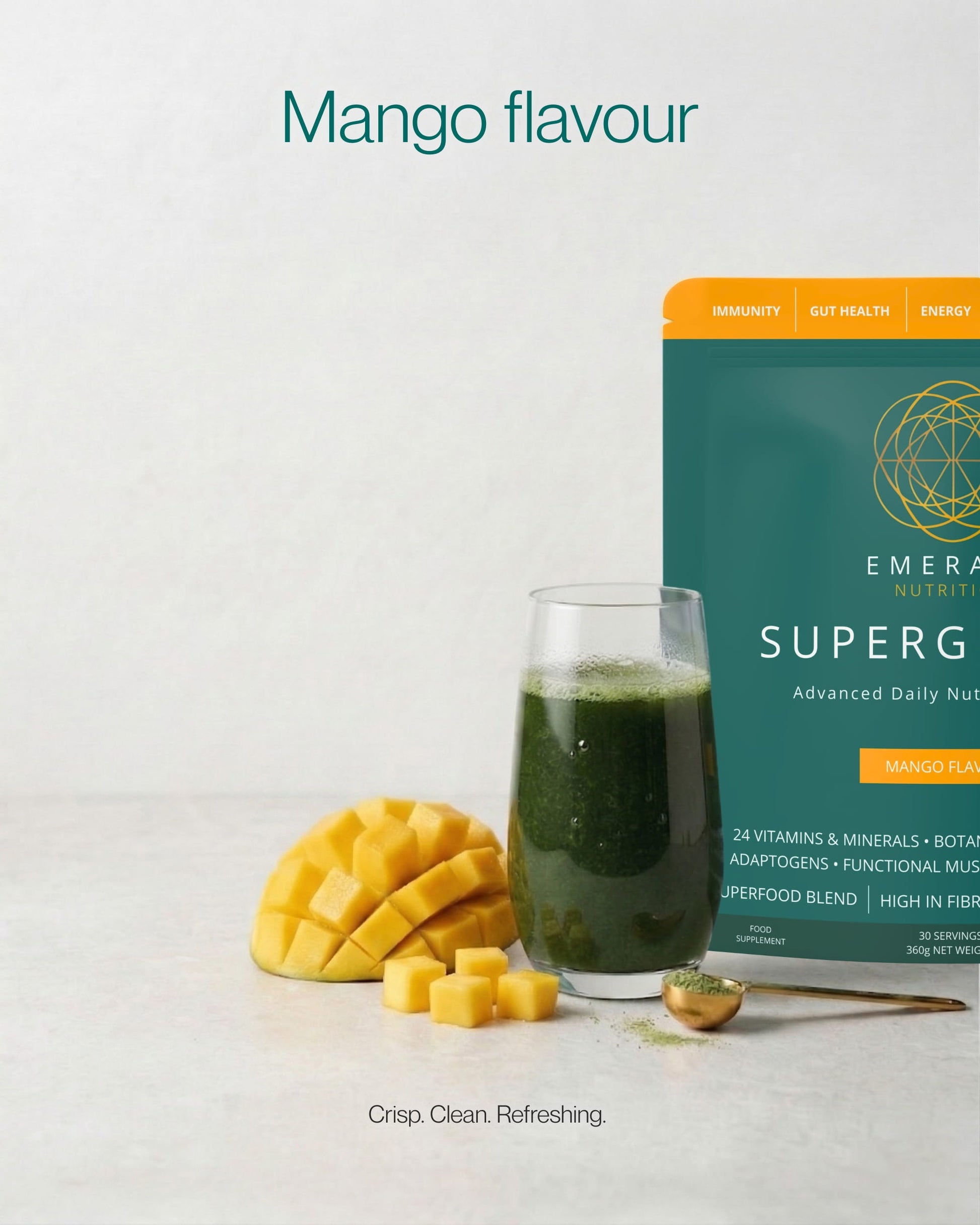 Emerald Nutrition SuperGreen package with a glass of green juice, mango pieces, and a spoon on a light background.