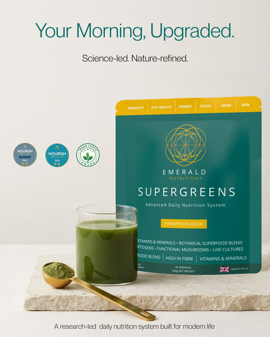 Emerald Nutrition Supergreens Pineapple Flavour pouch shown next to a glass of green drink and a gold spoon with green powder on a light stone slab, with marketing text above on a white background.