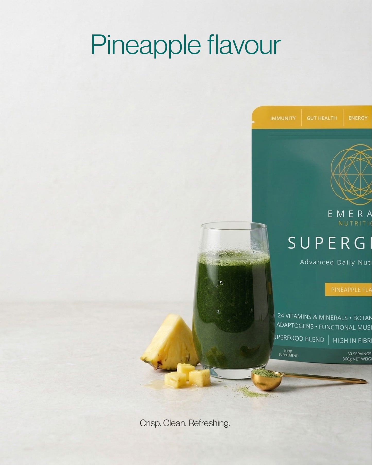 Emerald Nutrition SuperGreen package with a glass of green juice and pineapple on a light gray background