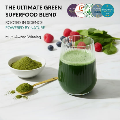 Green superfood blend with a glass of juice, bowl of matcha powder, and fresh berries on a white background.