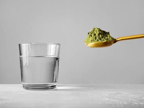 Green powder going into glass with water