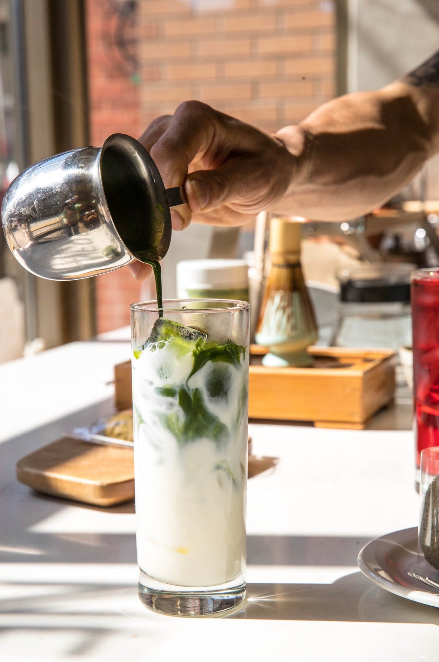 green liquid being poured into a glass of milk