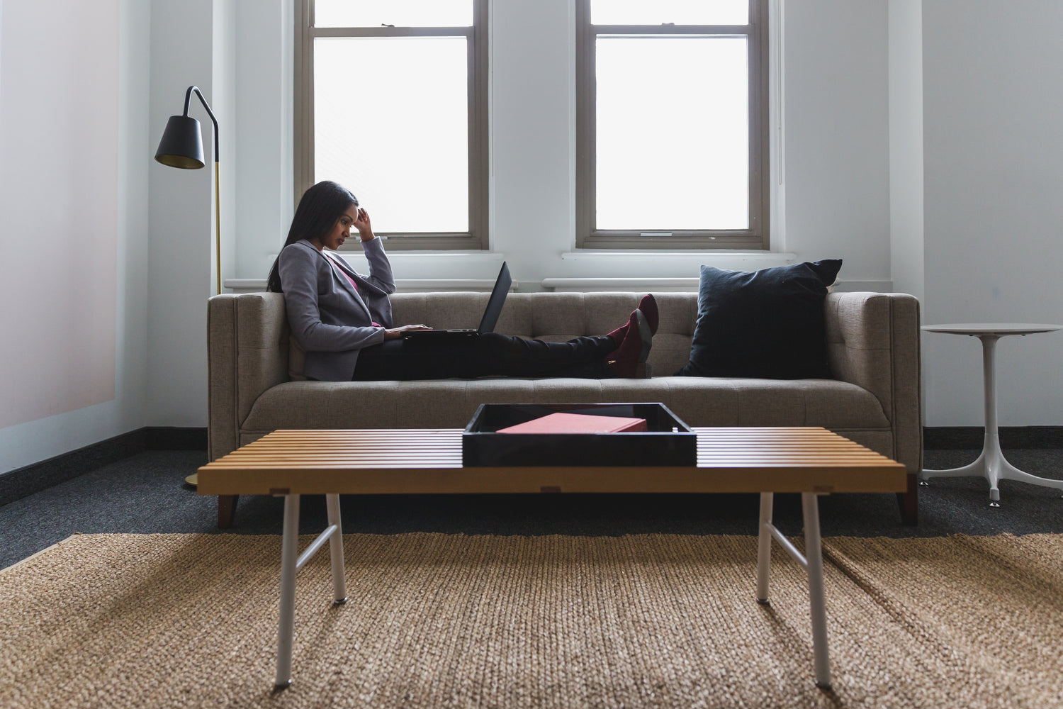 woman relaxed on sofa but working on laptop